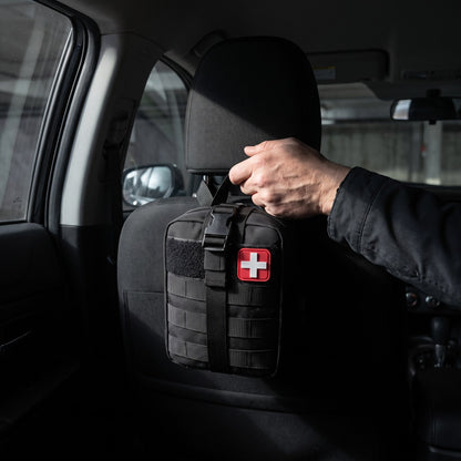 Phantom IFAK Kit strapped to the back of a car headrest, a hand reaching for the handle
