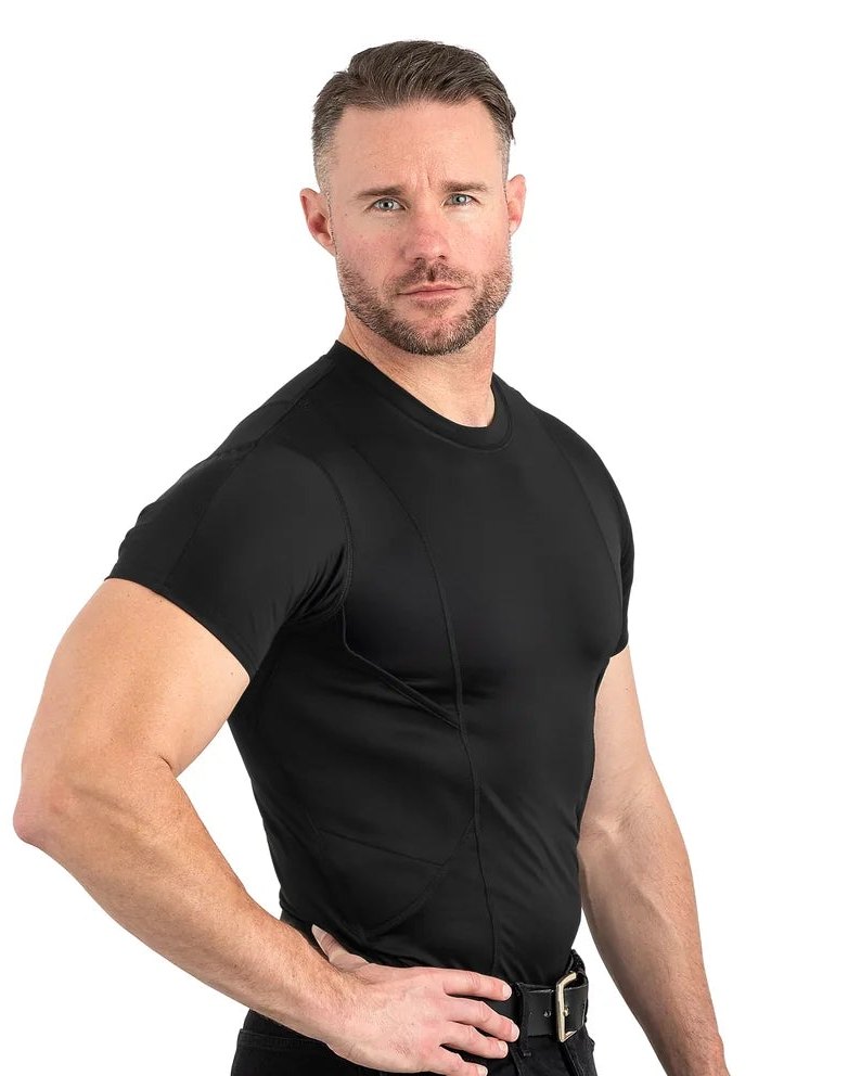 Muscular man in a black short-sleeve compression crew-neck shirt and black jeans, hand on hip, white background, side view