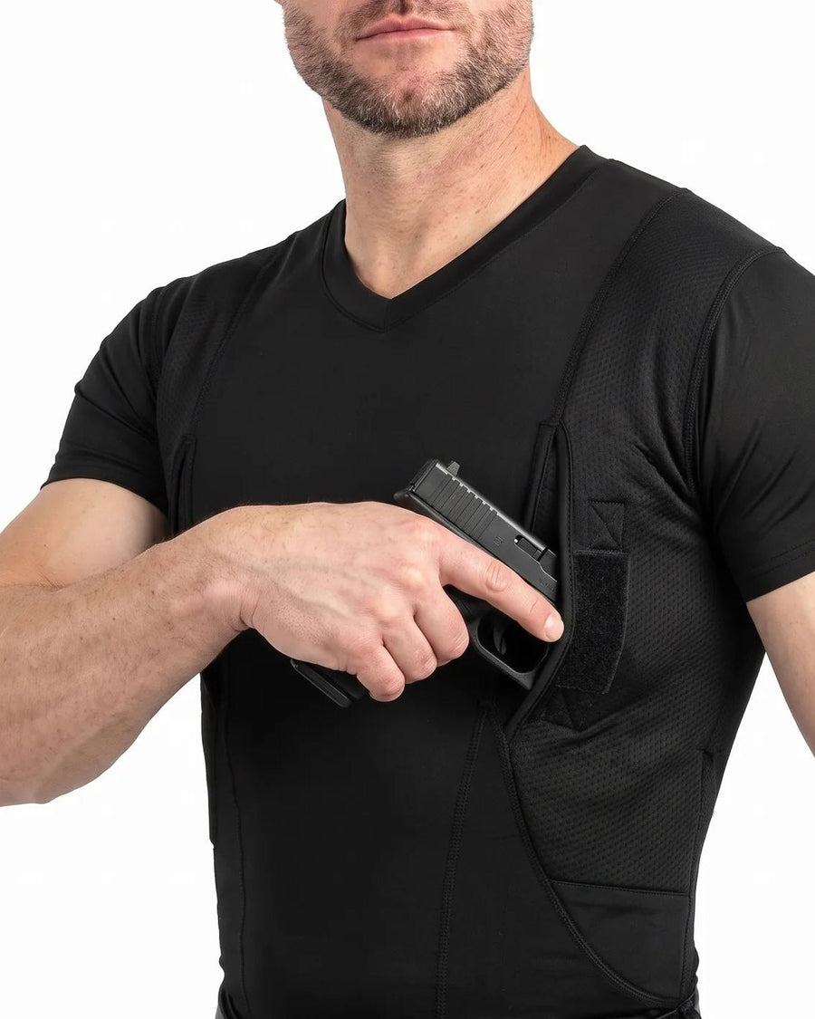 Man (face cropped at chin) in a black V-neck mesh-panel shirt drawing a pistol from the underarm pocket, white background